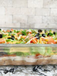 Mexican 9 Layer Dip in a pan with layers of refried beans and sour cream.
