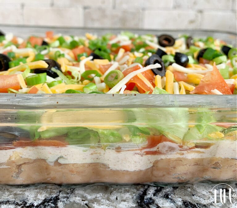 Up close photo of layers of chopped veggies and refried beans for Mexican dip.