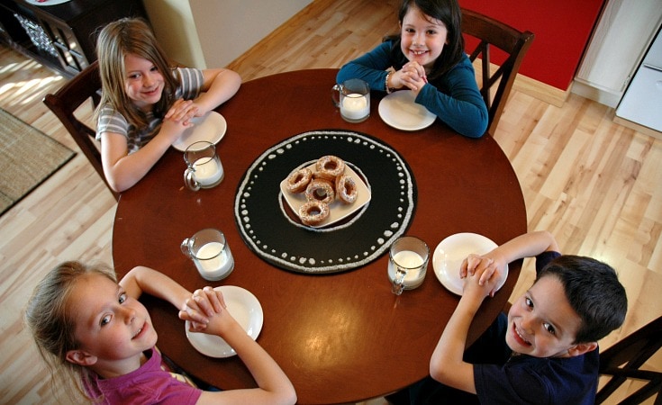 Four sweet kids sitting around a table waiting to eat homemade healthy donuts.