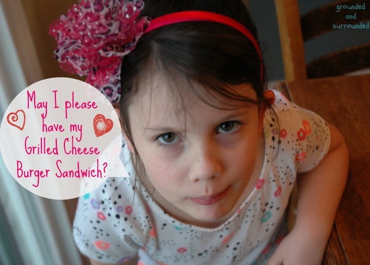 A little girl asking for her leftover grilled cheese burger sandwich.