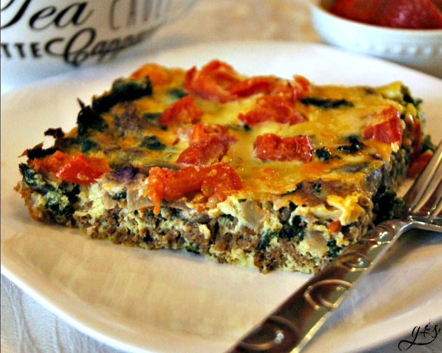 A close up of a healthy turkey sausage egg casserole  on a plate next to a coffee mug.