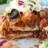 Side view of a piece of Mexican Lasagna topped with sour cream and cilantro.