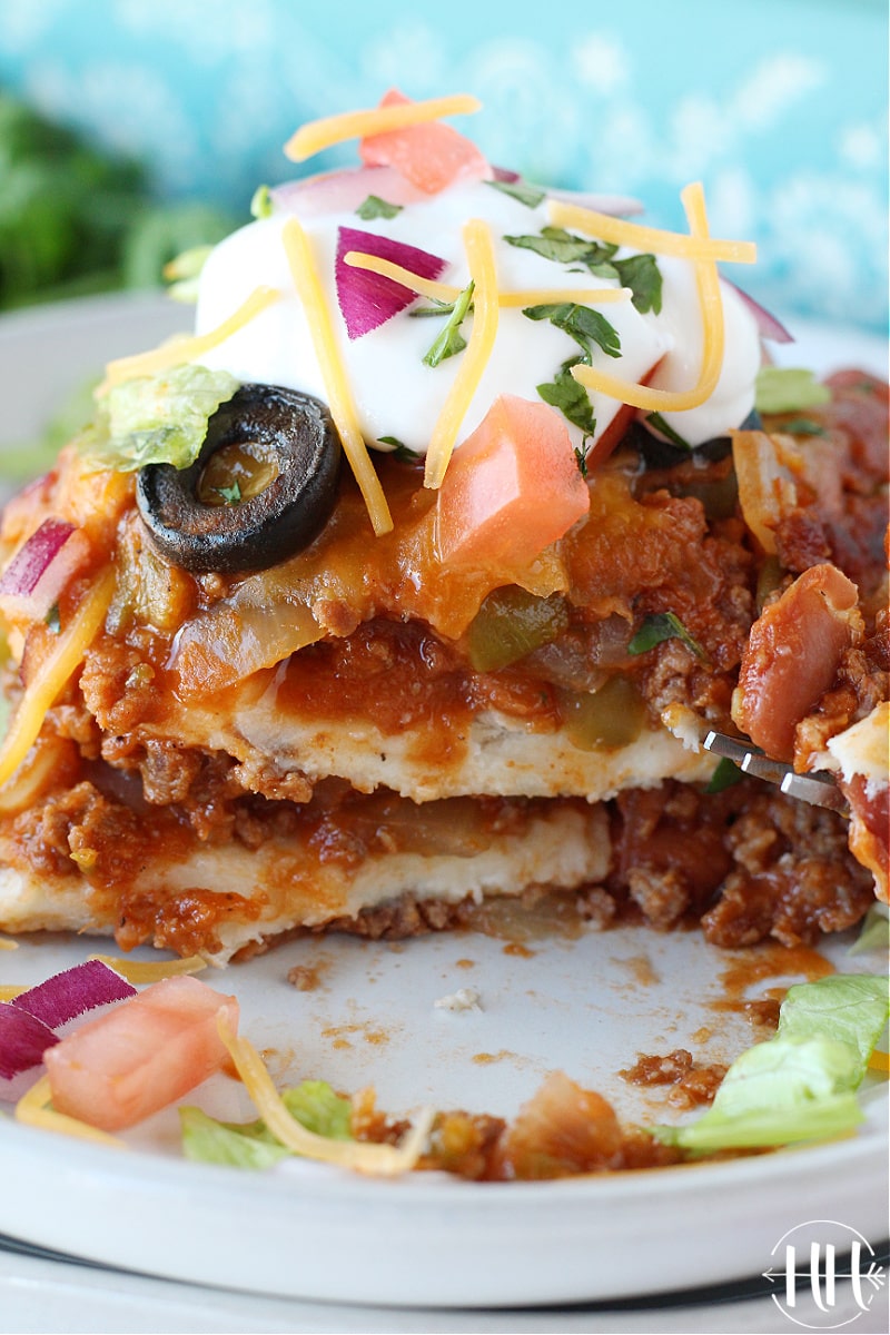 Beautiful shot of a piece of Healthy Mexican Lasagna on a white place topped with plain Greek yogurt.