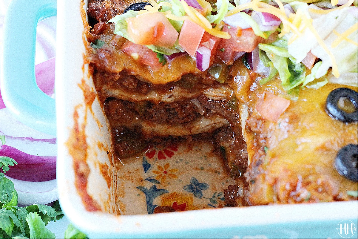 A Mexican casserole using gluten free tortillas in a pretty white and turquoise pan.