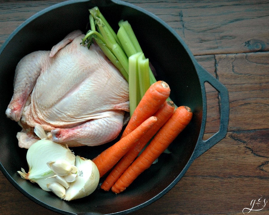 Learn how to boil a chicken! Overhead photo of large whole chicken and vegetables. 