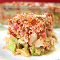 Cabbage roll lasagna on a white plate near the pan of lasagna.