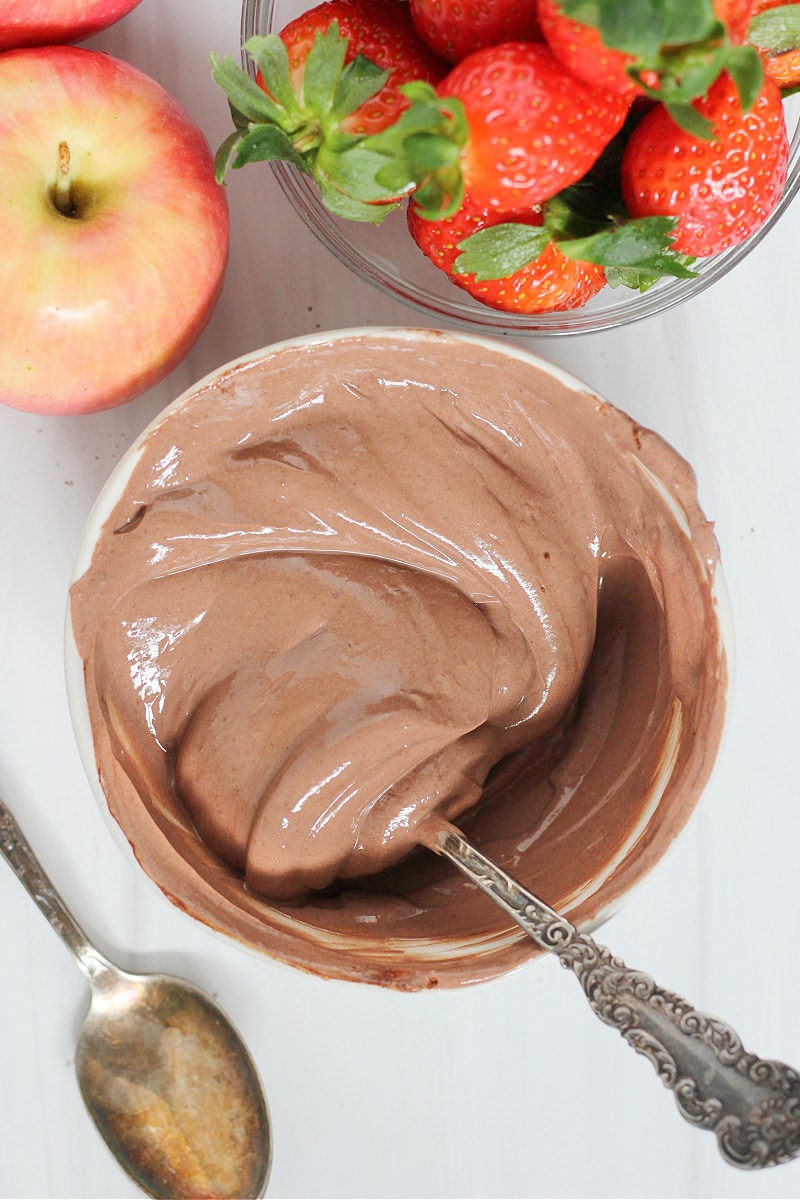 A spoon stirring a bowl of high protein chocolate yogurt dip.
