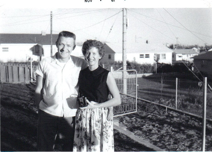 A black and white photo of a couple in the 1960s by their vegetable garden.