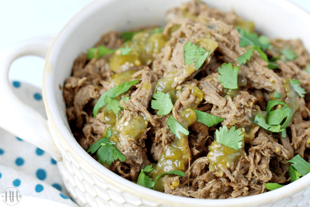 A bowl of roast beef with salsa verde drizzled and chopped cilantro. 