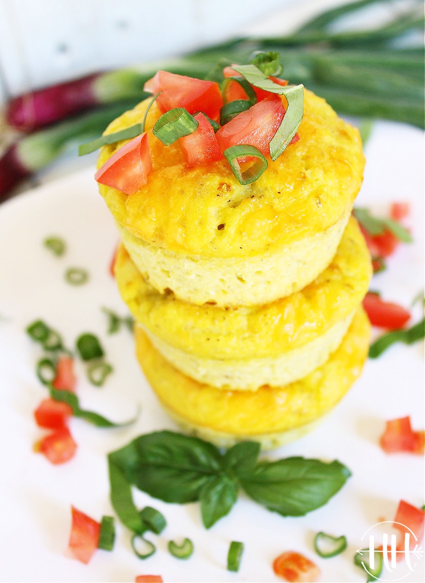 A stack of mini frittatas garnished with diced tomato and julienned basil.