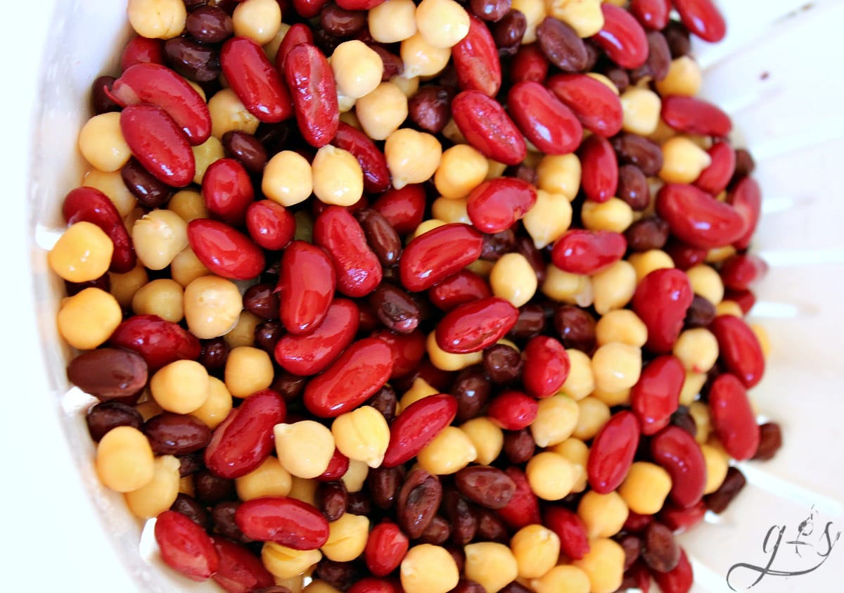 Kidney beans, chickpeas, and black beans rinsed in a white colander.