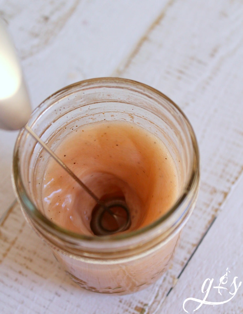 A matcha frother mixing together a simple salad dressing in a mason jar.