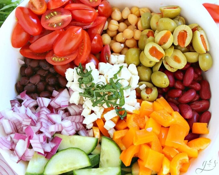 Overhead photo of the ingredients for a Mediterranean bean salad in a white bowl.