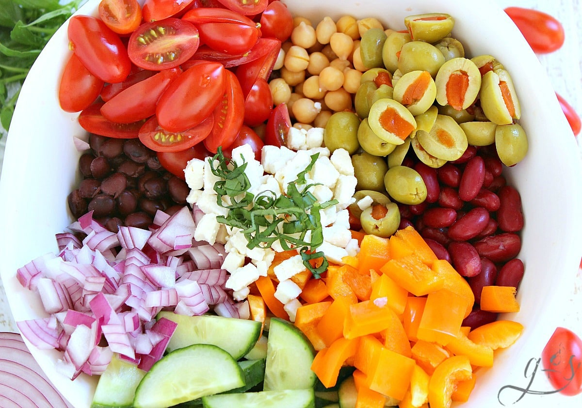 Overhead photo of the ingredients for a Mediterranean bean salad in a white bowl.