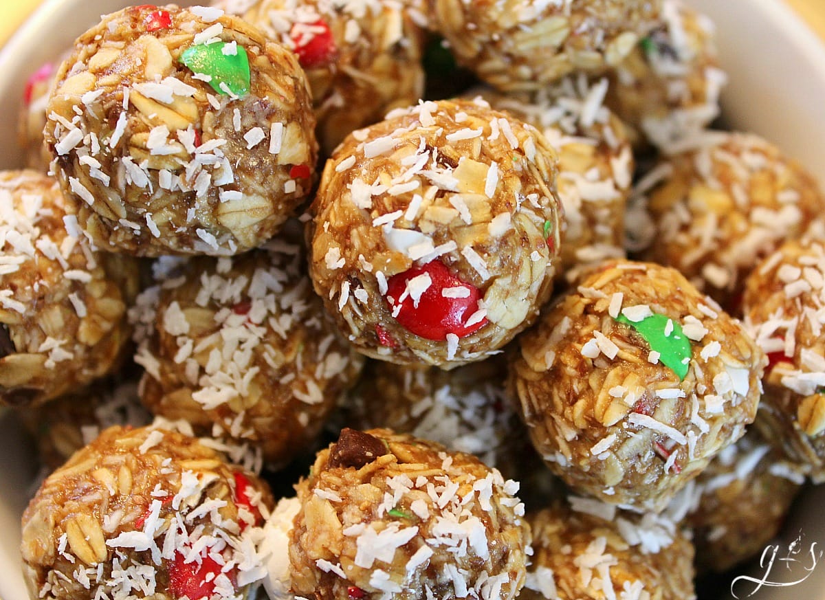 The BEST 6 Ingredient Christmas Energy Bites | This healthy no bake recipe is easy and quick to prepare. Oatmeal, flaxseed (or hemp seeds), peanut butter, M&Ms, honey, and "snow" aka finely shredded coconut make up these homemade gluten free goodies. Make these raw bites for kids and adults alike. Think monster cookie, but with 5 simple whole food ingredients!