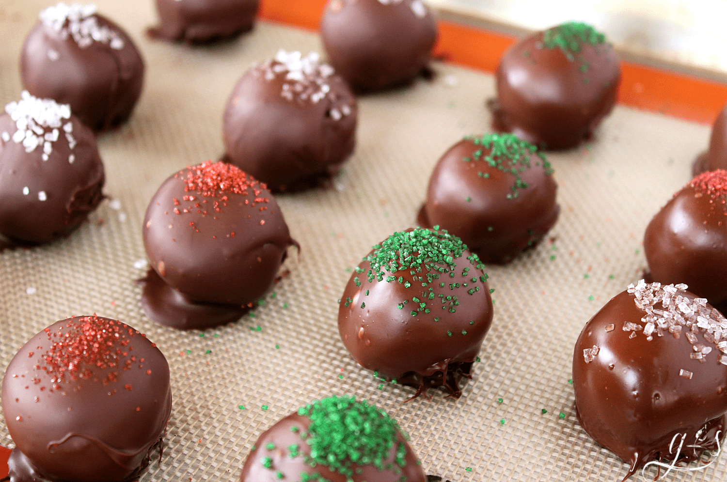 A tray of hot cocoa truffles sprinkled with green and red sanding sugar.