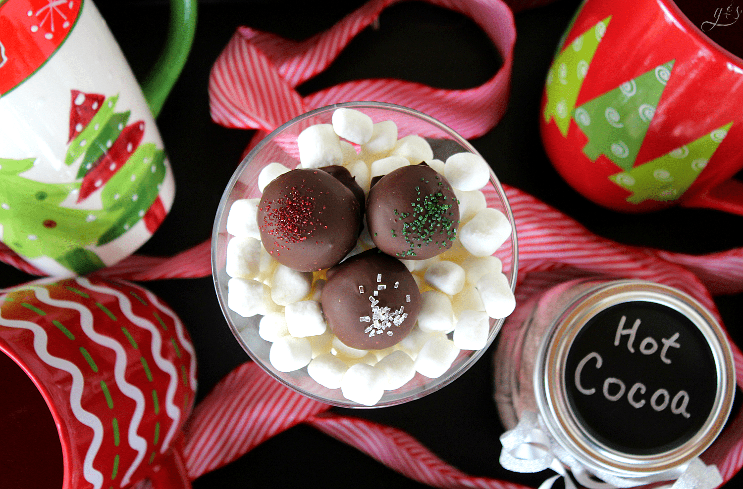 Three beautiful hot cocoa truffles on a bed of mini marshmallows.