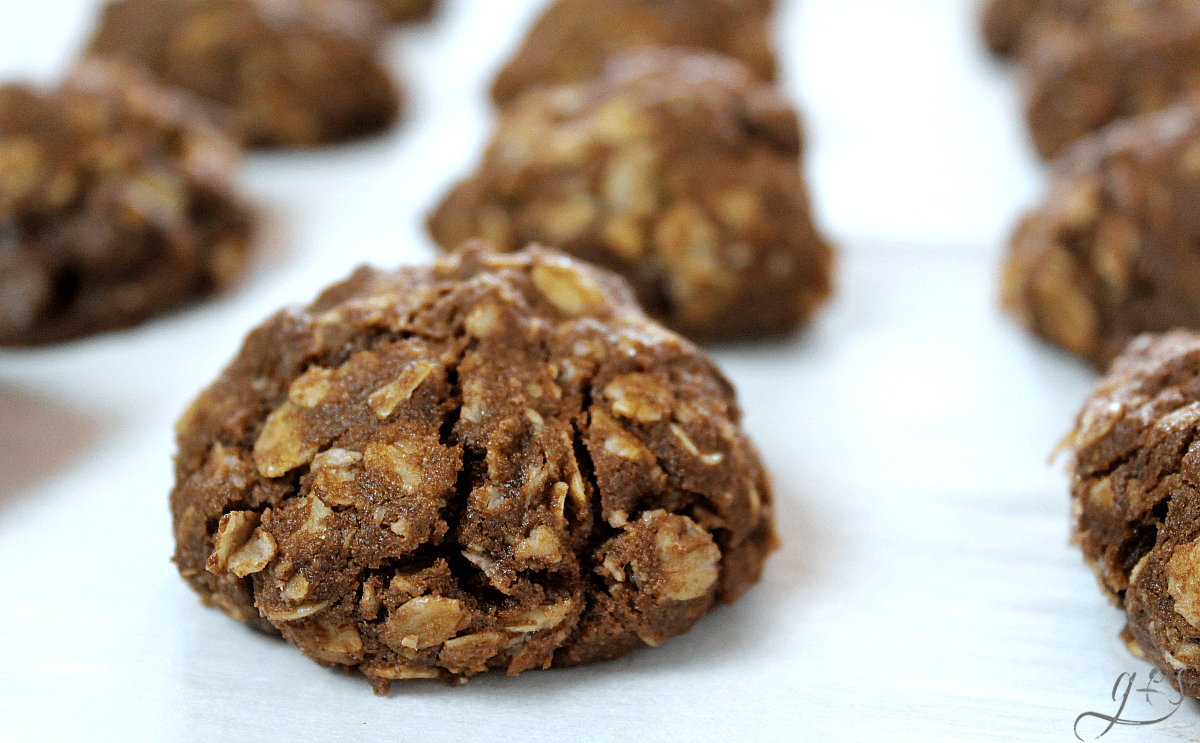 Double chocolate oatmeal cookies baked on a parchment paper lined baking sheet.