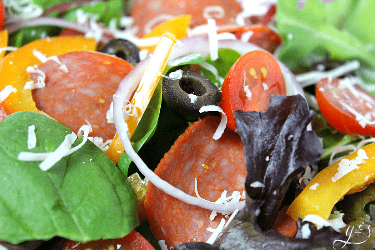 The BEST Clean Eating Pizza Salad | This is one of my favorite healthy and low carb lunch ideas! It is a delicious gluten free recipe complete with turkey pepperoni for protein, homemade tomato-based dressing, shredded Parmesan cheese, and veggies. Meals like this are great for one or families. Just pile high the toppings on a whole bag of greens and triple the sauce! Give this easy and flavorful salad a try if you are in a food rut!