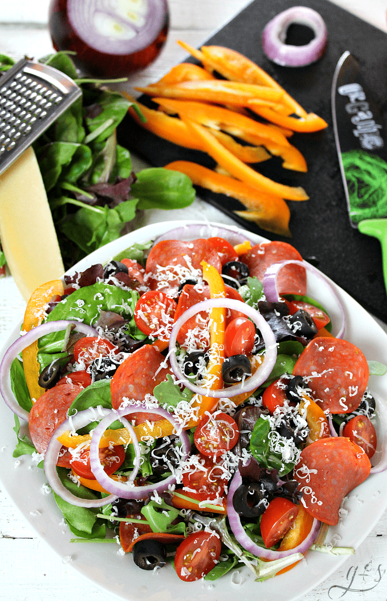 The BEST Clean Eating Pizza Salad | This is one of my favorite healthy and low carb lunch ideas! It is a delicious gluten free recipe complete with turkey pepperoni for protein, homemade tomato-based dressing, shredded Parmesan cheese, and veggies. Meals like this are great for one or families. Just pile high the toppings on a whole bag of greens and triple the sauce! Give this easy and flavorful salad a try if you are in a food rut!