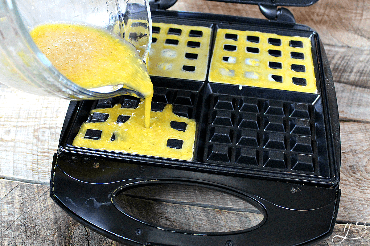 Pouring a cheesy egg mixture in a waffle iron. 