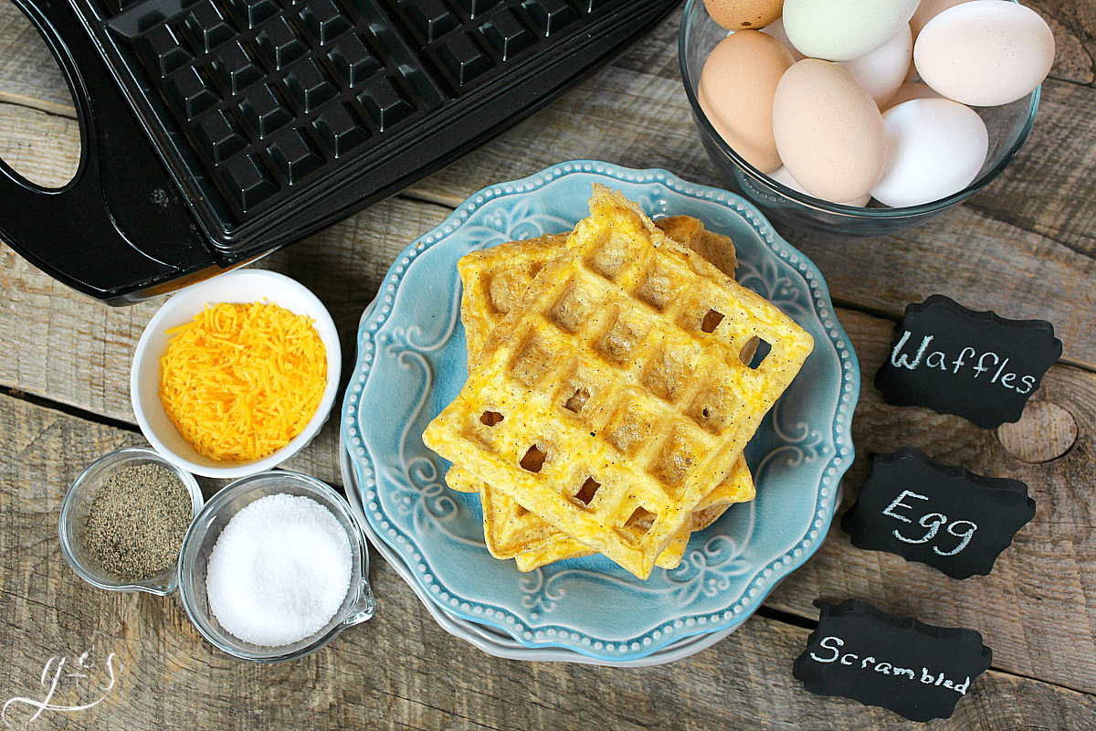 A birds eye view of a stack of scrambled egg waffles next to a waffle iron.