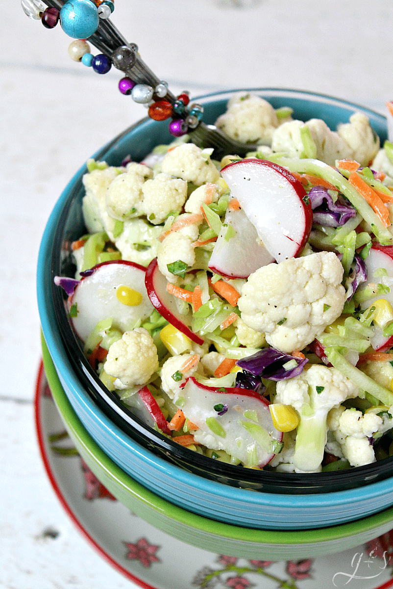 The BEST Cauliflower & Broccoli Slaw Salad | Say hello to the newest healthy and gluten free salad and homemade dressing recipes on the block! Add fresh radish and corn(fresh or frozen) to the main ingredients. Then a little clean eating mayo, fresh chopped basil, and a couple other easy pantry ingredients to the sauce. Eat this as a vegetarian meal for dinner and lunch or to feed a crowd. Spring and summer are my favorite seasons to eat this low carb and vegan side salad!