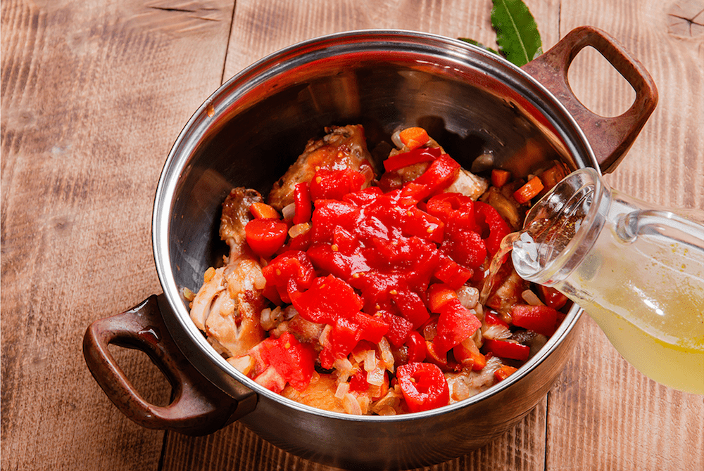 Pouring broth in a large soup pot.