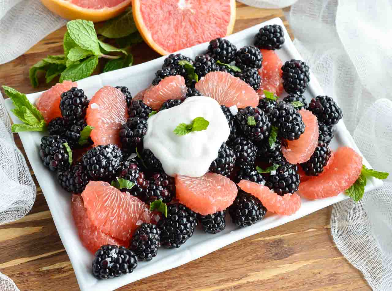 Blackberry and grapefruit salad on a white plate. 