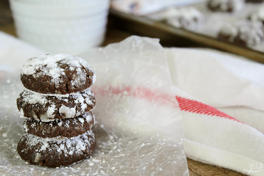 Stacked chocolate crinkle cookies covered in powdered sugar.
