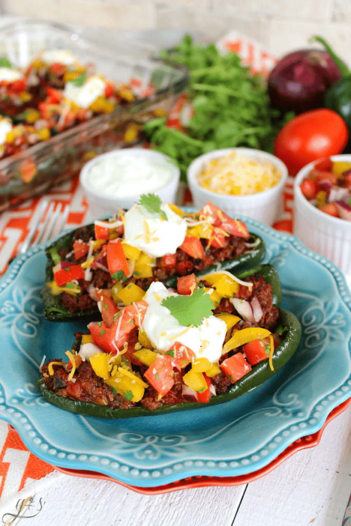 The BEST Clean Eating Stuffed Poblano Peppers | This easy Mexican dinner is healthy, gluten-free, low carb, and keto friendly. Use any ground meat (beef, buffalo, turkey, venison), shredded cheese, and top with a fresh homemade bell pepper salsa. Think of these as a healthy take on tacos by adding plain Greek yogurt (sour cream), avocado, and additional salsa to this delicious recipe. Make Paleo by omitting the cheese or use beans in place of the meat to make it vegetarian!