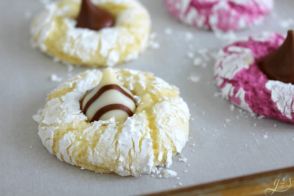 Beautiful white crinkle cookie covered in powdered sugar with a Hershey Hug in the middle. 