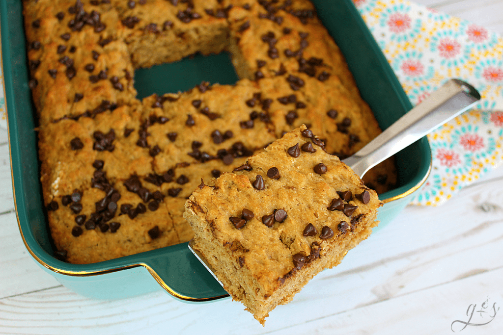 A slice of Banana Bread Brownies held by a spatula atop the pan. 