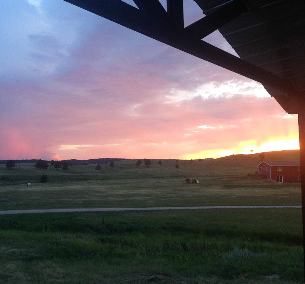 Gorgeous sunset with blue, purple, pink, yellow, and orange hues from a craftsman front porch of a new home. 