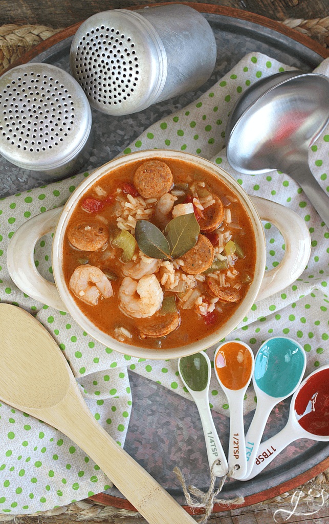 Vertical shot of a bowl of gumbo jambalaya with two bay leaves on top. 