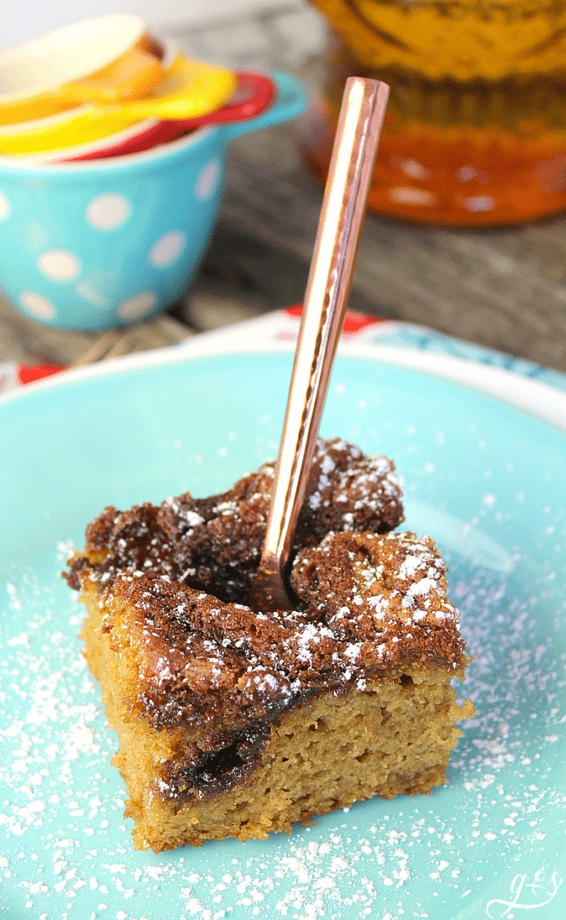 Beautiful copper fork in a moist coffee cake aka gluten free cowboy bread with ceramic measuring cups in the background.