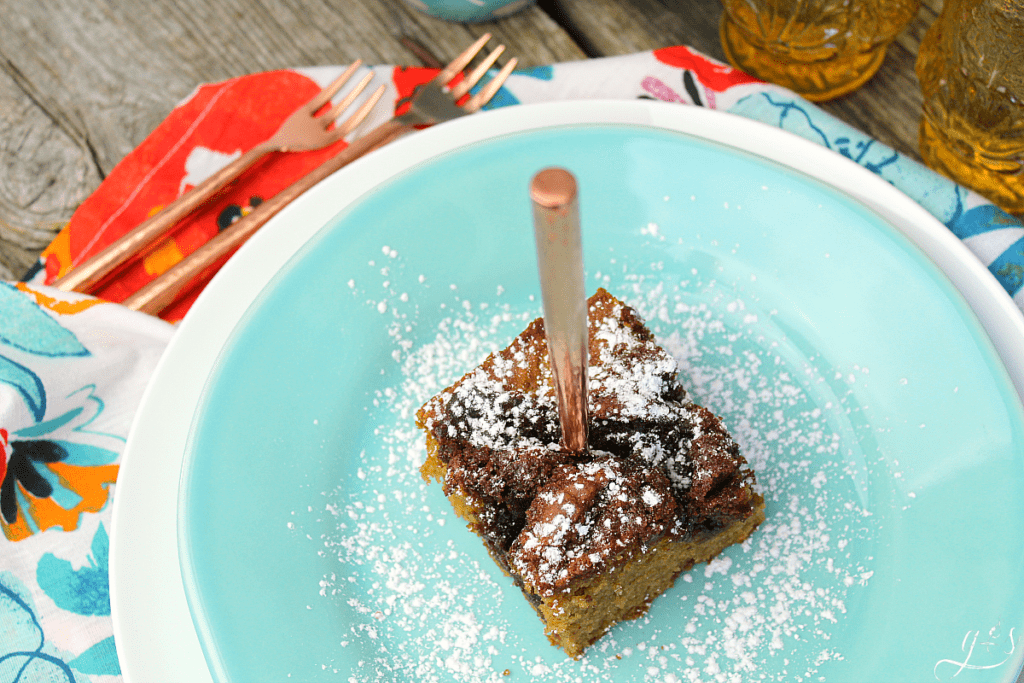 Bird's eye view of a slice of Cowboy Bread sprinkled with powdered sugar and a copper fork stuck in it for dramatic detail.