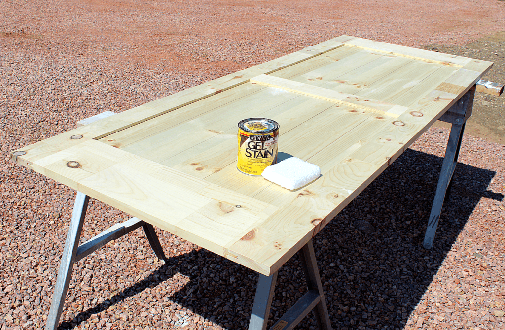 Gel stain container and cotton stain applicator sitting on untreated barn door. 