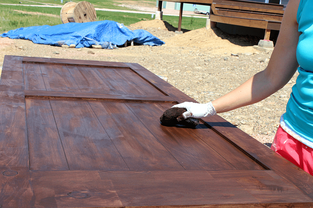 Applying gel stain with cotton pad on barn door. 