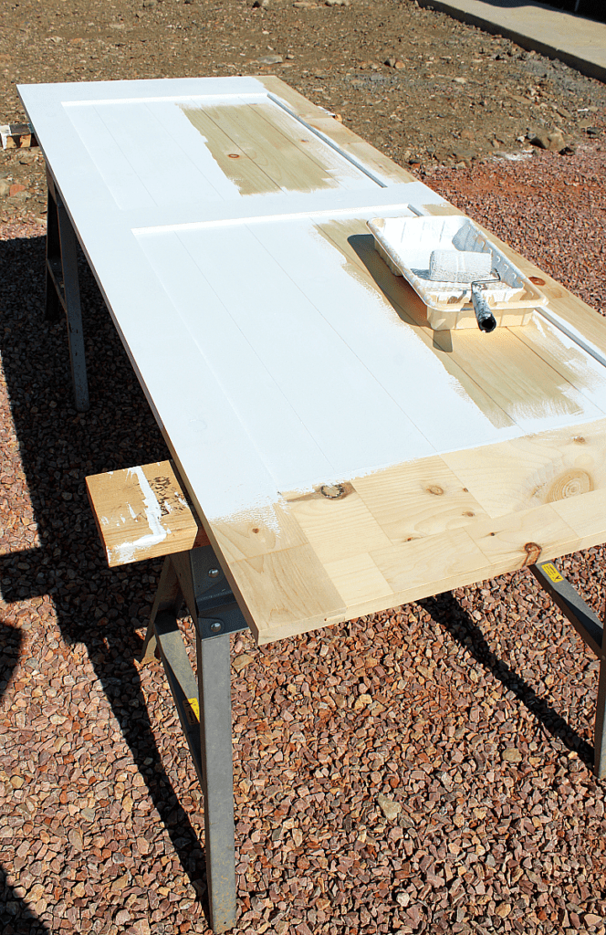 4 inch roller applying white chalkboard paint to barn door. 