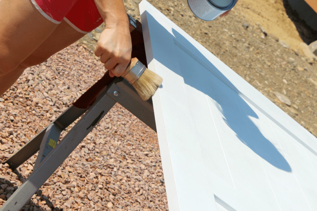 Applying Annie Sloan clear wax to seal a white chalkboard barn door. 