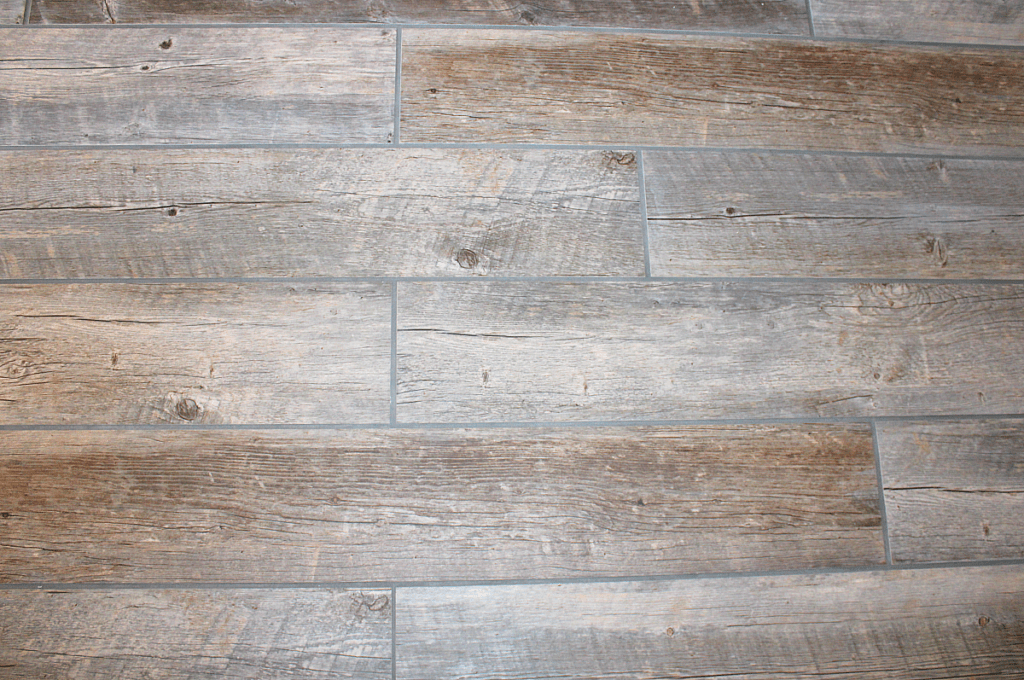 Completed tile floor in bathroom using long wood-look tile porcelain planks.