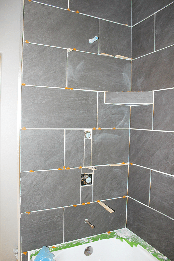 Photo of cut tiles around pipes and valves in shower surround. 