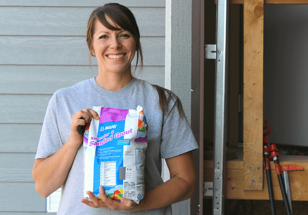 Happy girl holding a bag of sanded grout outside. 