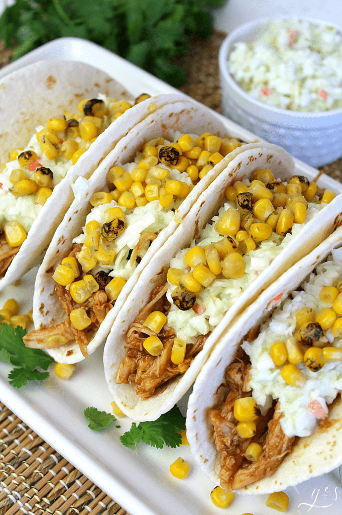 The BEST BBQ Chicken Tacos | This easy 5 ingredient recipe makes the perfect quick weeknight dinner. Rotisserie chicken, barbecue sauce, store-bought coleslaw, a can of fire-roasted corn, and flour or corn tortillas are all you need! Mexican food is a favorite in our family but these summer street taco flavors can't be beat. #bbq #tacos #chicken #dinners #recipes 