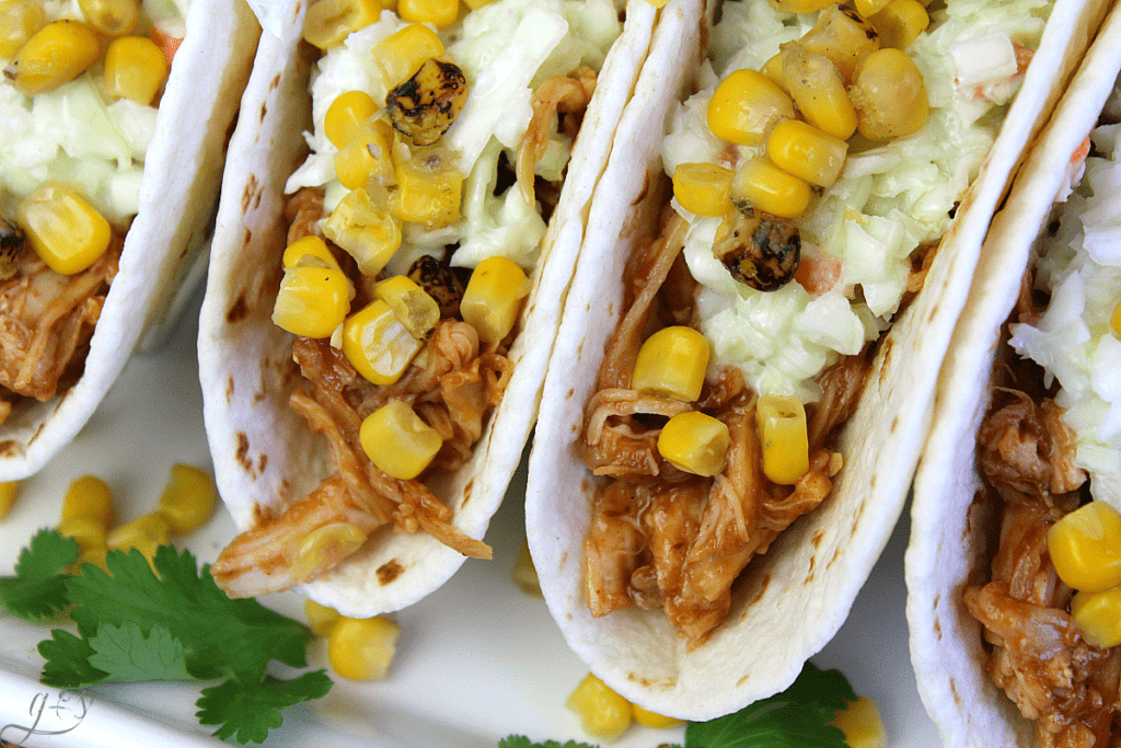 Up close shot of BBQ Chicken Street Tacos with barbecue chicken, coleslaw, and fire-roasted corn in a flour tortilla.