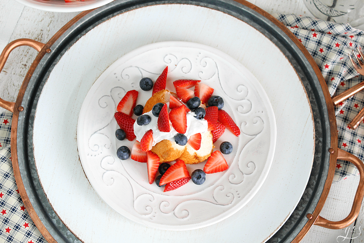 Overhead shot of red white and blue shortcake. Store-bought angel food cake strawberries, blueberries, and coconut whipped cream. 