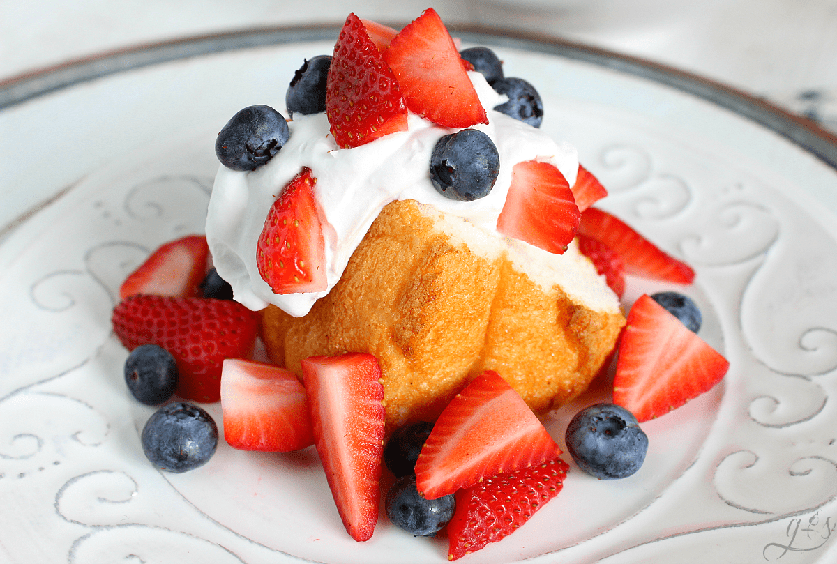 Patriotic Shortcake on a white plate complete with angel food cake, berries, and coconut whipped cream.