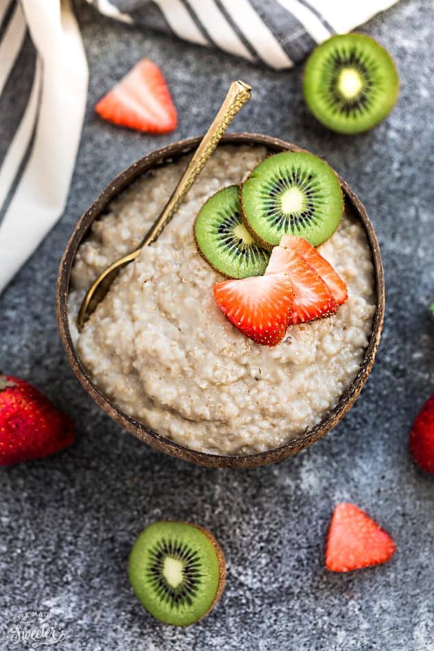 Bowl of steel cut oats topped with sliced of kiwi and strawberries. 
