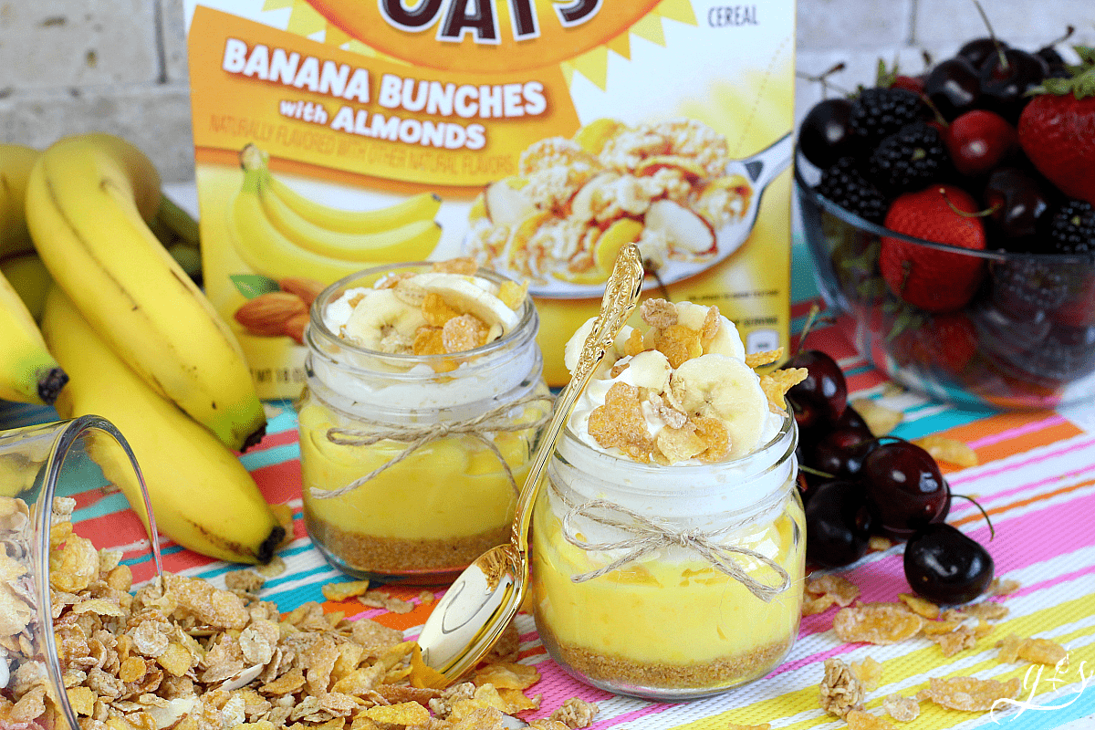 Honey Bunches of Oats cereal tipped out of a cup with bananas, pie jars, and berries. 